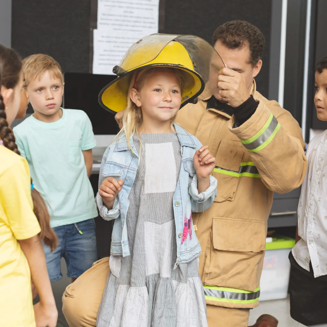 a fire officer offering his helmet to a student in class for fire safety drill.