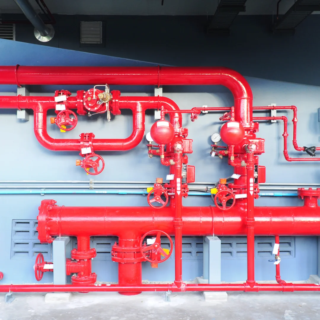 a set of red painted of fire pipelines installed in a building with varius pressure gauges and valves, contols etc