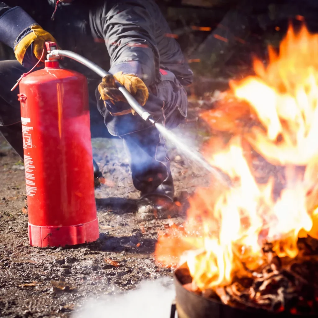 a man holding a fire extinguishers and trying to put out the flame with the help of extinguishers